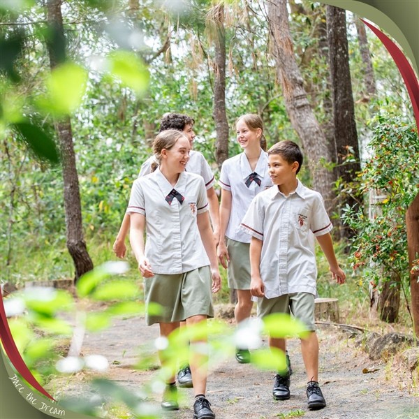 Students walking together along a bushland path in school uniform.